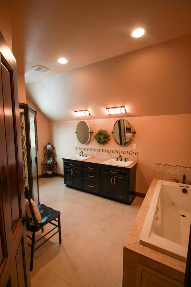 bathroom with lofted ceiling, tiled tub, and vanity