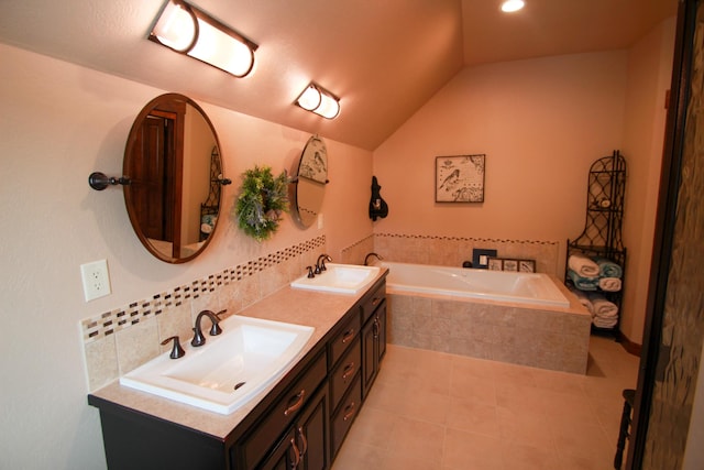 bathroom with vaulted ceiling, tile patterned floors, backsplash, vanity, and a relaxing tiled tub