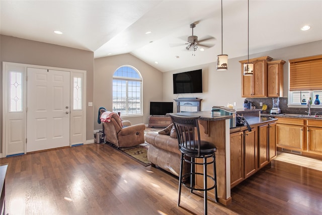 kitchen featuring a breakfast bar area, a center island, dark hardwood / wood-style flooring, lofted ceiling, and tasteful backsplash