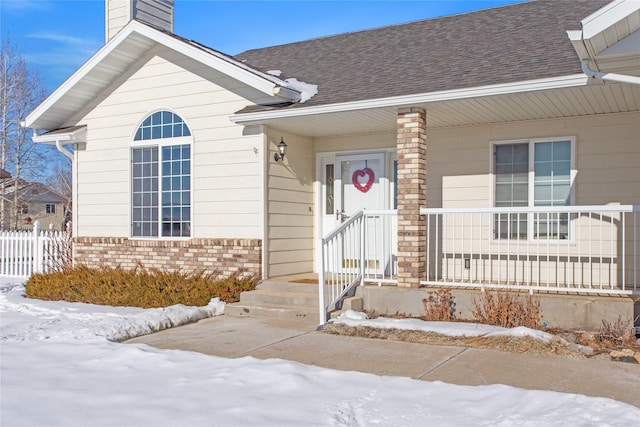 snow covered property entrance featuring covered porch