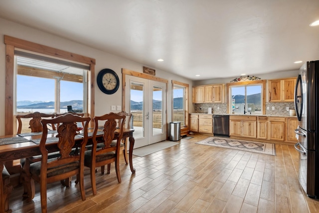 kitchen featuring stainless steel dishwasher, black fridge, light hardwood / wood-style floors, tasteful backsplash, and a mountain view