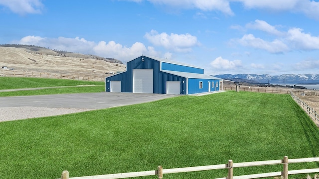 exterior space with a garage, a rural view, a mountain view, and a yard