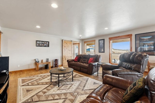 living room with a barn door and light hardwood / wood-style flooring