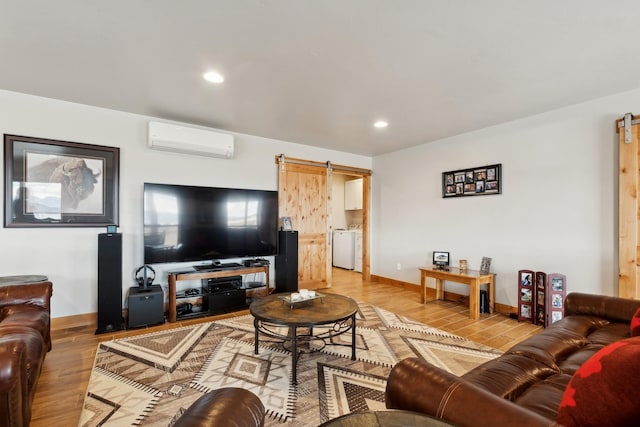 living room featuring washer / clothes dryer, a wall mounted AC, a barn door, and wood-type flooring