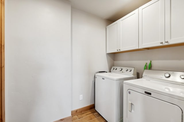 clothes washing area featuring washer and dryer and cabinets