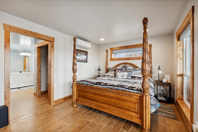 bedroom featuring ensuite bath, a notable chandelier, a wall mounted air conditioner, and multiple windows