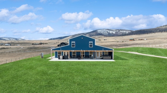 back of property featuring a patio, a yard, a rural view, and a mountain view