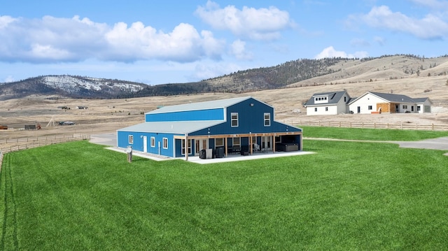 rear view of house with a lawn and a mountain view