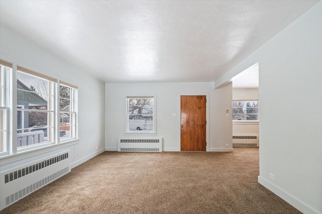 unfurnished room featuring a textured ceiling, carpet floors, and radiator