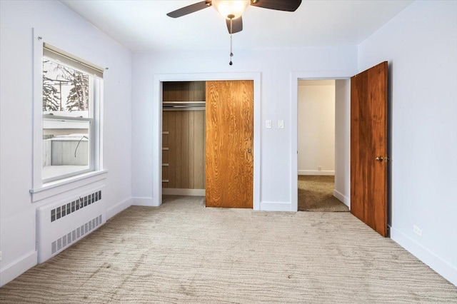 unfurnished bedroom with a closet, light colored carpet, ceiling fan, and radiator heating unit