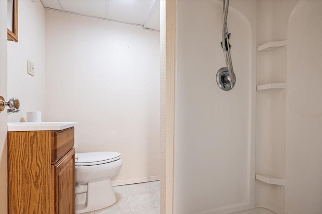 bathroom with toilet, a shower, a drop ceiling, tile patterned floors, and vanity