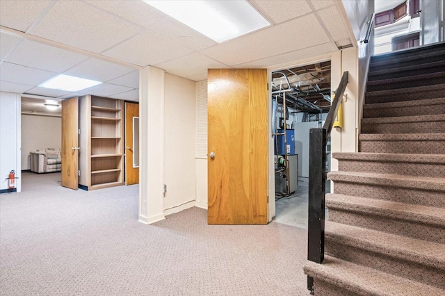 basement featuring gas water heater, a paneled ceiling, and carpet flooring