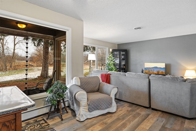 living room featuring baseboard heating, a textured ceiling, and wood-type flooring