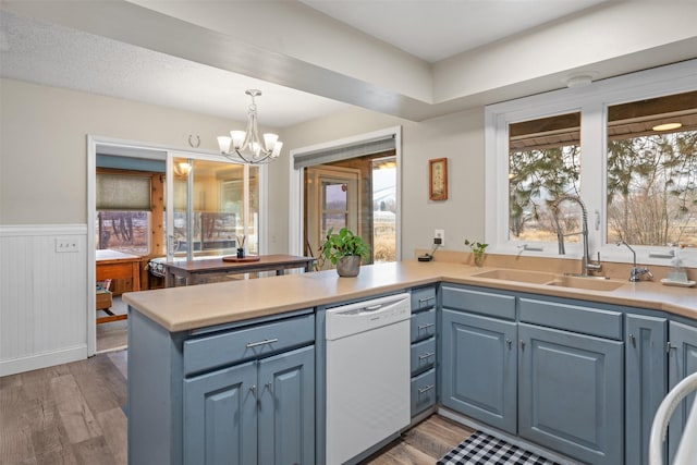 kitchen with dishwasher, decorative light fixtures, an inviting chandelier, blue cabinets, and sink