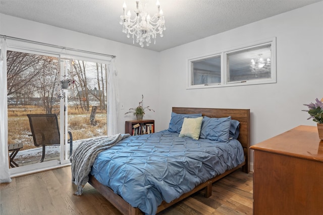 bedroom with a textured ceiling, hardwood / wood-style floors, and a chandelier