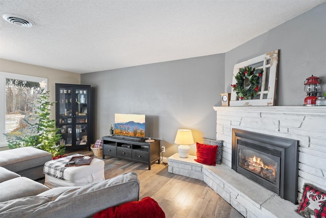 living room with a fireplace, a textured ceiling, and light hardwood / wood-style floors