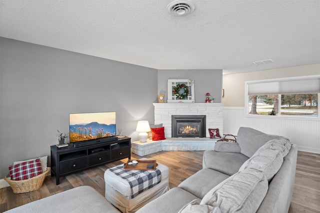 living room with a fireplace, a textured ceiling, and dark hardwood / wood-style floors