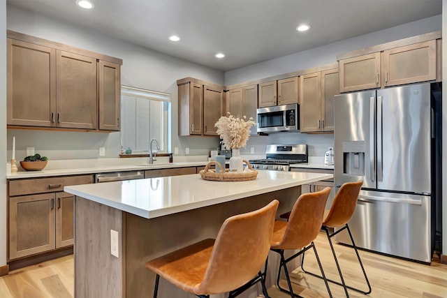 kitchen featuring stainless steel appliances, a center island, light wood-type flooring, and a kitchen breakfast bar