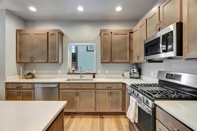 kitchen with appliances with stainless steel finishes, light hardwood / wood-style flooring, and sink