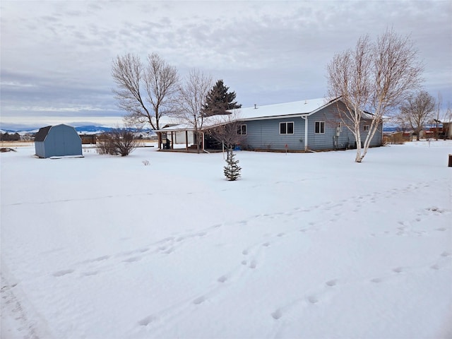 snow covered house with a storage shed and an outdoor structure