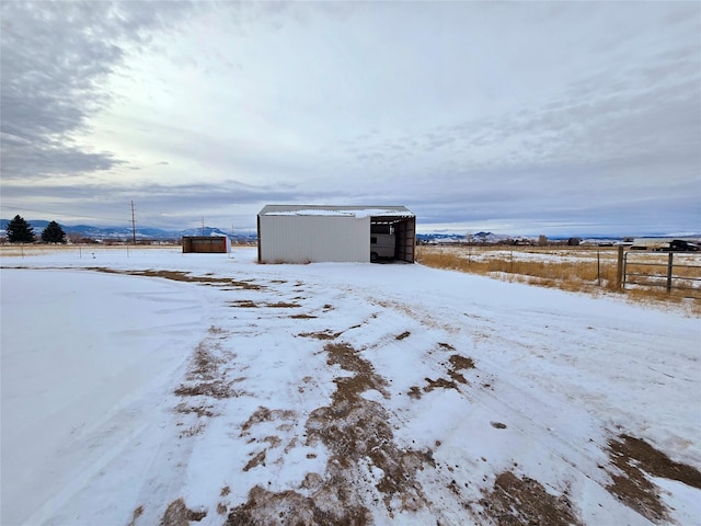 snowy yard with a rural view and an outdoor structure