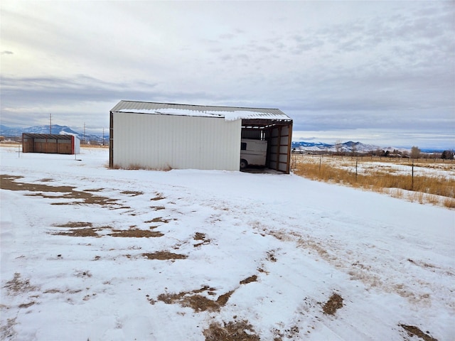 snow covered structure with a carport, an outbuilding, and a pole building