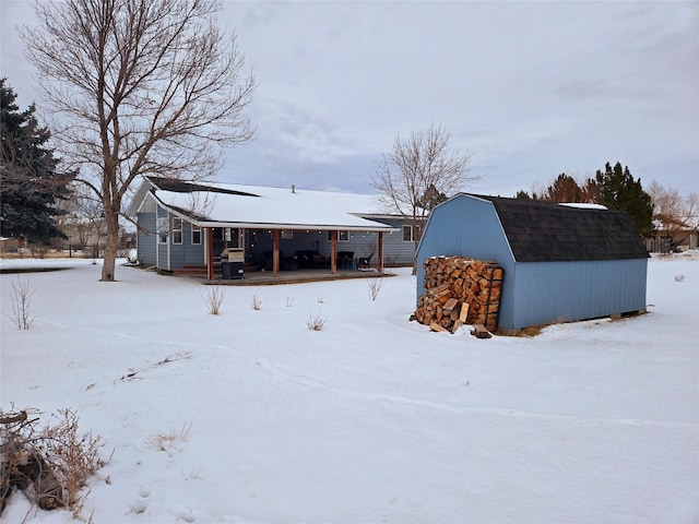 snow covered structure with an outbuilding and a storage shed