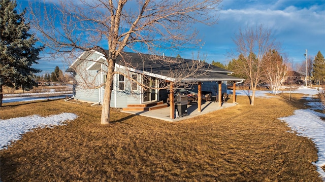 snow covered property with a patio area and a lawn