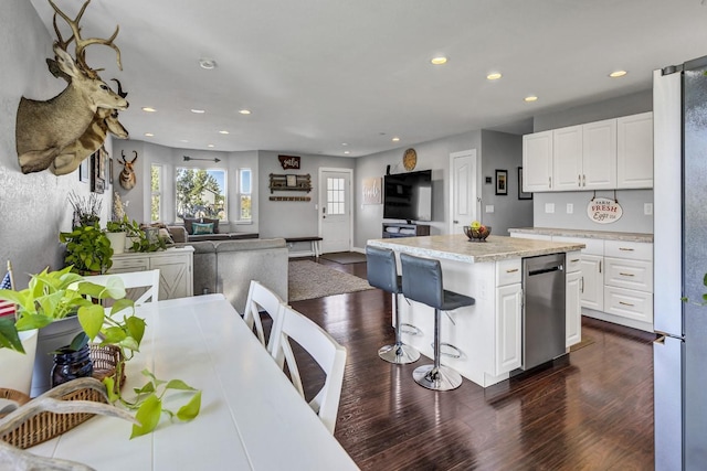 kitchen featuring a breakfast bar area, appliances with stainless steel finishes, dark hardwood / wood-style flooring, a kitchen island, and white cabinetry