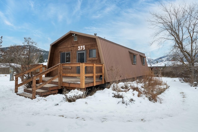 snow covered back of property featuring a mountain view