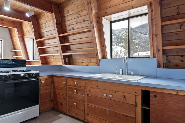 kitchen with wood ceiling, gas range oven, wooden walls, a mountain view, and sink