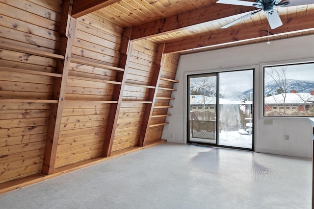 empty room with wooden walls, a mountain view, wooden ceiling, ceiling fan, and beamed ceiling