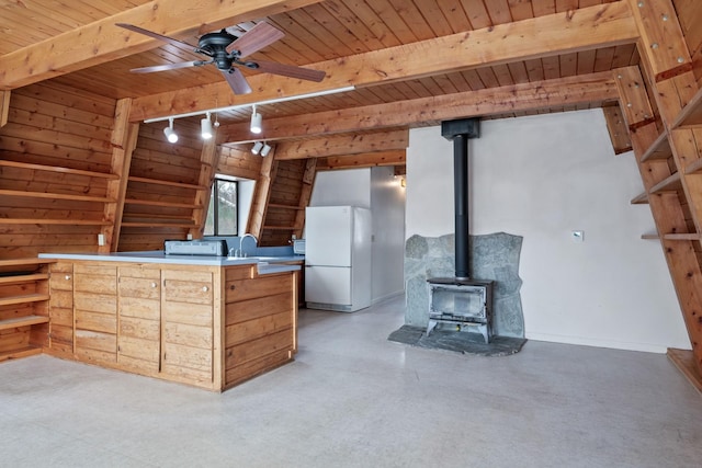 kitchen featuring beamed ceiling, wood ceiling, white fridge, and a wood stove