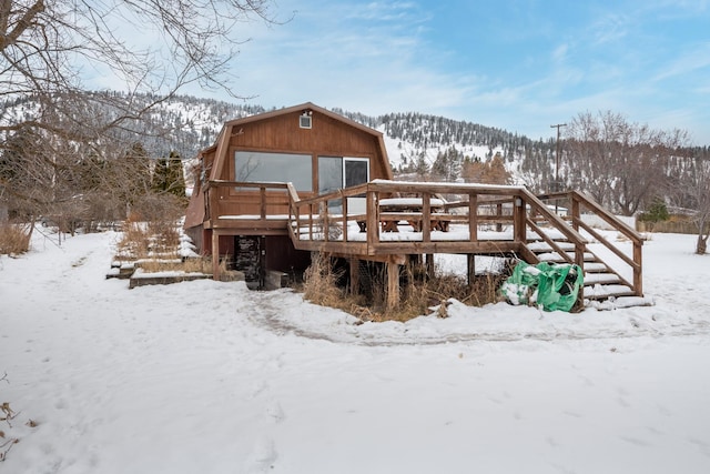 snow covered rear of property featuring a deck with mountain view