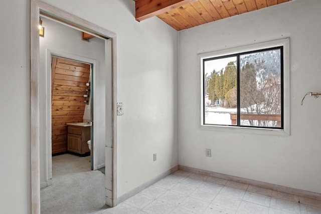 empty room featuring wooden ceiling and beamed ceiling