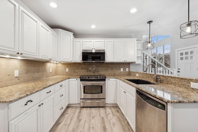 kitchen featuring appliances with stainless steel finishes, white cabinets, decorative light fixtures, and sink