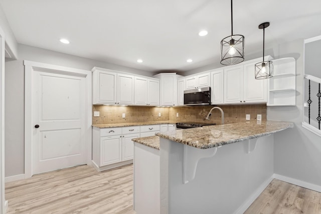 kitchen featuring decorative light fixtures, kitchen peninsula, tasteful backsplash, and white cabinetry