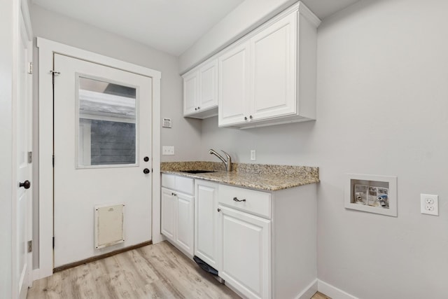 clothes washing area with sink, cabinets, light wood-type flooring, and washer hookup