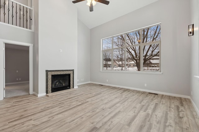 unfurnished living room featuring high vaulted ceiling, ceiling fan, and light wood-type flooring