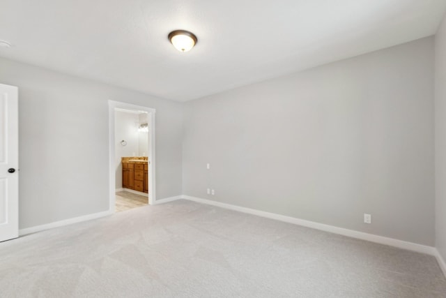 unfurnished bedroom featuring ensuite bathroom and light carpet