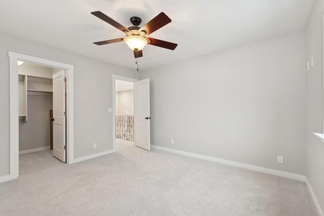 unfurnished bedroom with light colored carpet, ceiling fan, a spacious closet, and a closet