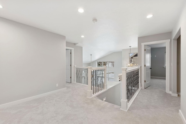 hallway featuring lofted ceiling and light carpet