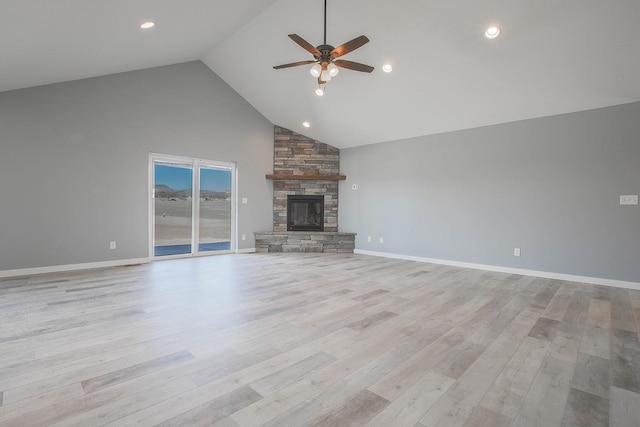 unfurnished living room featuring high vaulted ceiling, ceiling fan, light hardwood / wood-style flooring, and a stone fireplace