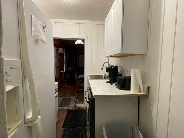 kitchen featuring white refrigerator with ice dispenser, white cabinets, dark wood-type flooring, and sink