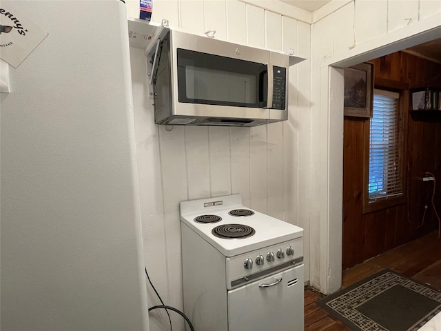 kitchen with white electric range, wooden walls, refrigerator, and dark hardwood / wood-style flooring