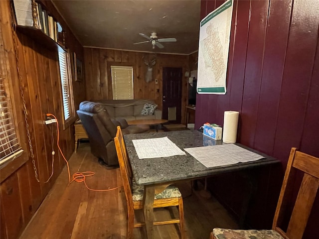 dining area featuring ceiling fan, wood walls, and hardwood / wood-style flooring