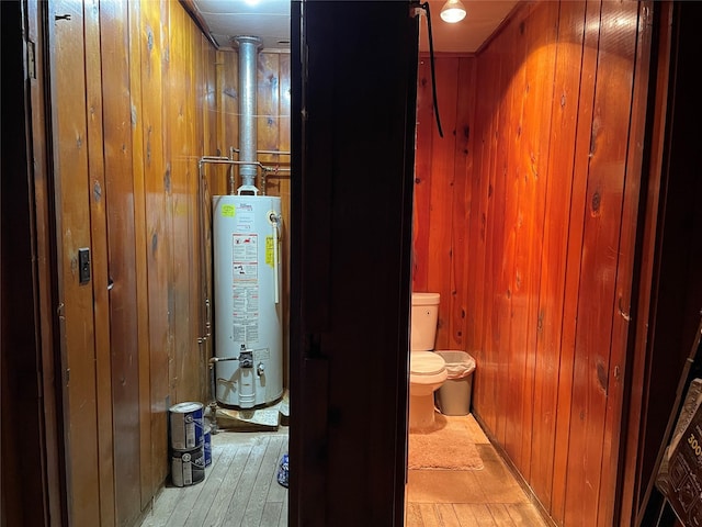 bathroom with wooden walls, water heater, and toilet