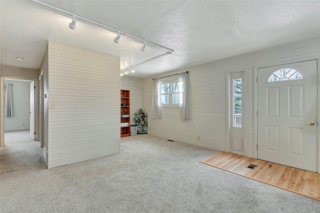 carpeted foyer entrance with rail lighting and a textured ceiling