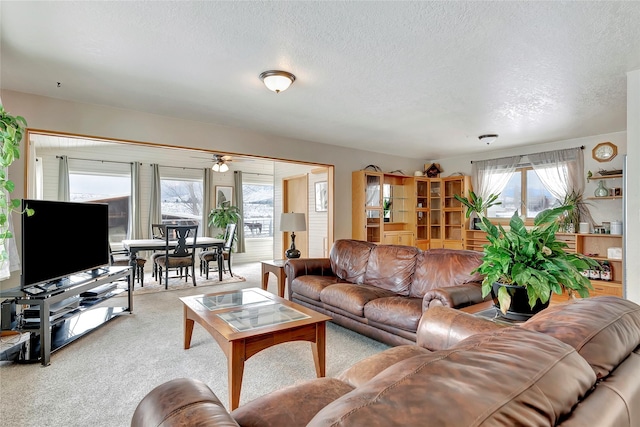 carpeted living room featuring a textured ceiling, ceiling fan, and a wealth of natural light