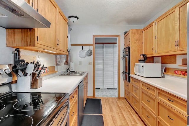 kitchen featuring appliances with stainless steel finishes, light brown cabinets, sink, light hardwood / wood-style flooring, and range hood